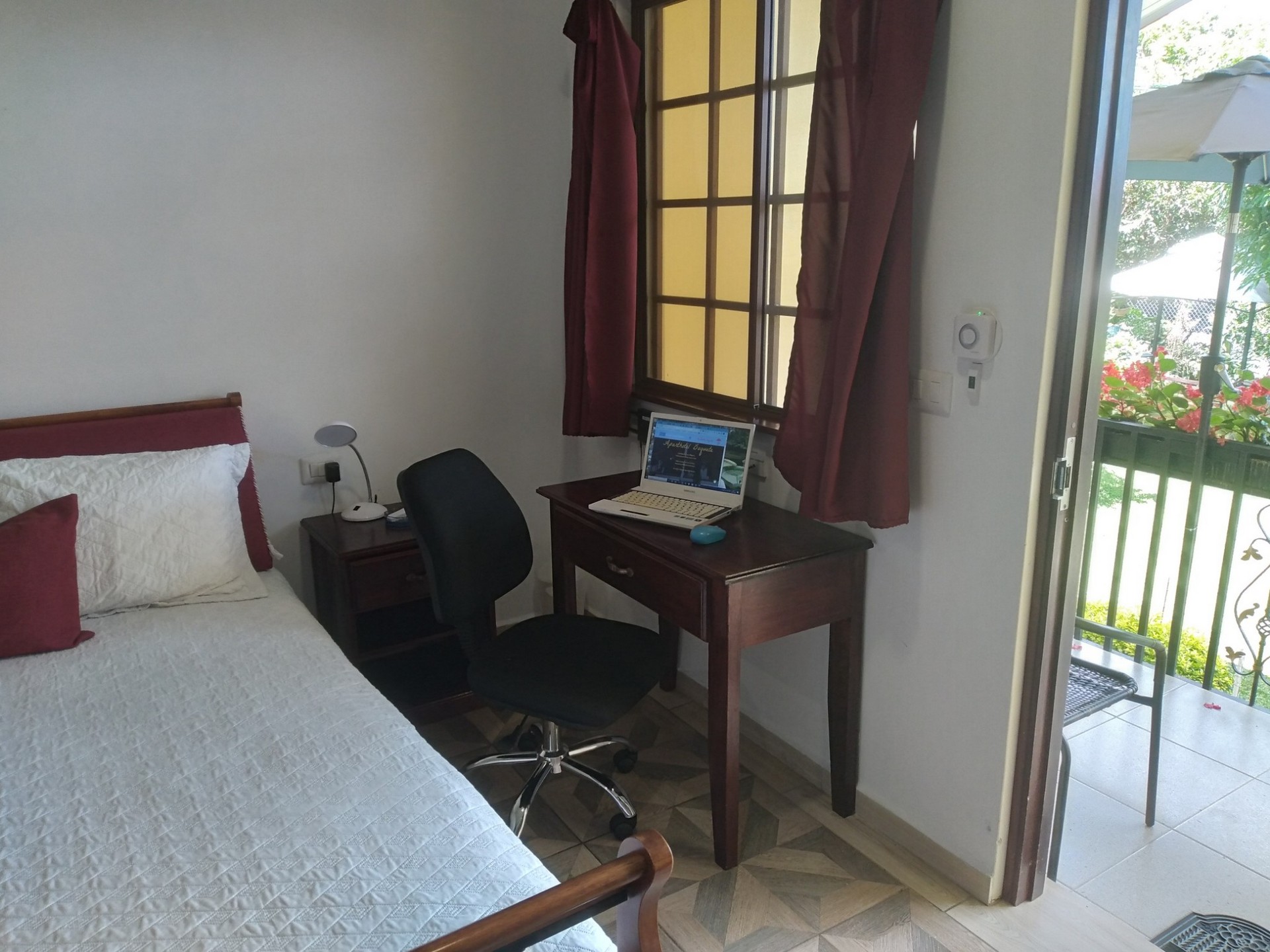 bed with nightstand with desk, laptop and comfortable office chair
