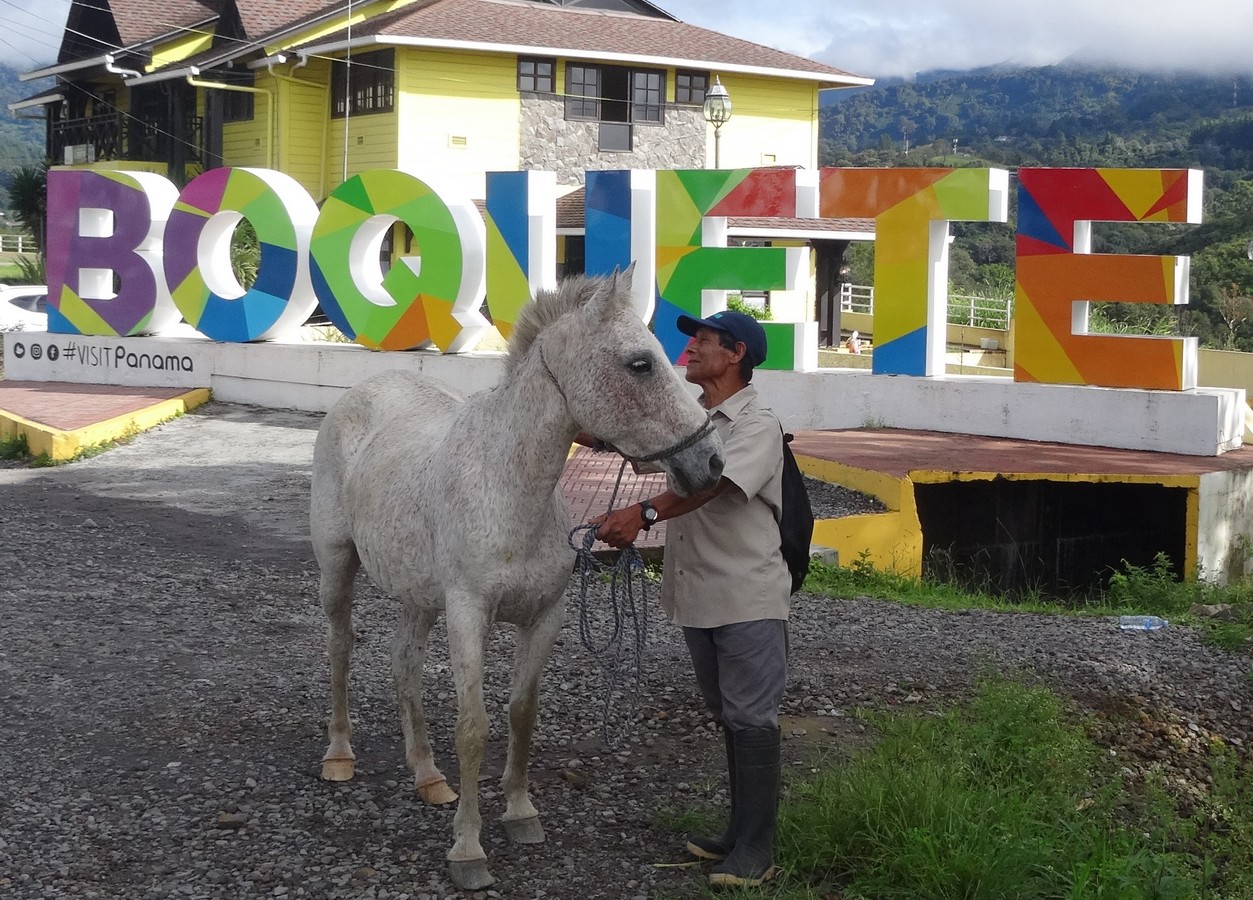 A man with a horse at the BOQUETE sign at the entry to Bajo Boquete (CEFATI building)